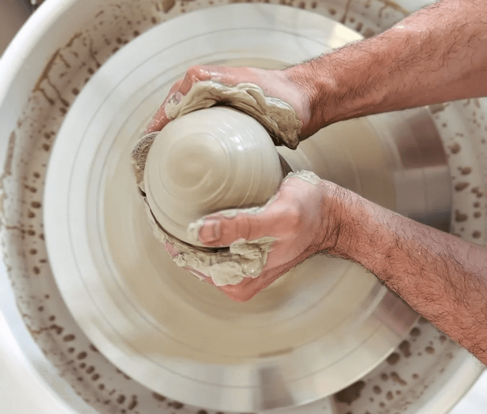 Hands centering clay on a pottery wheel